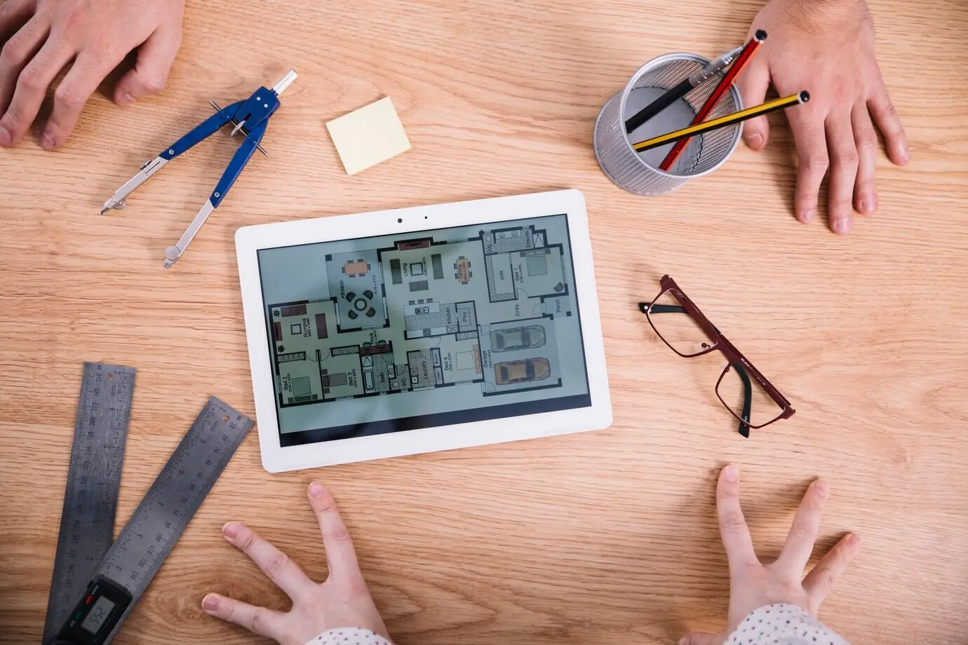 Cropped view of hands near a tablet with a blueprint.